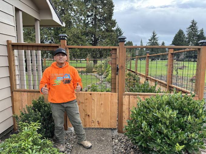 A man standing in front of a wooden fence