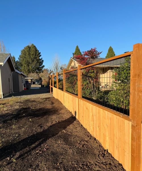 A wooden fence with plants growing on top of it