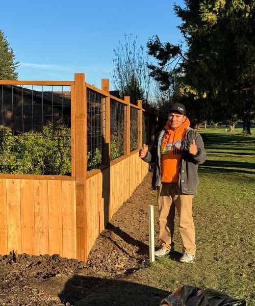 A man standing next to a wooden fence