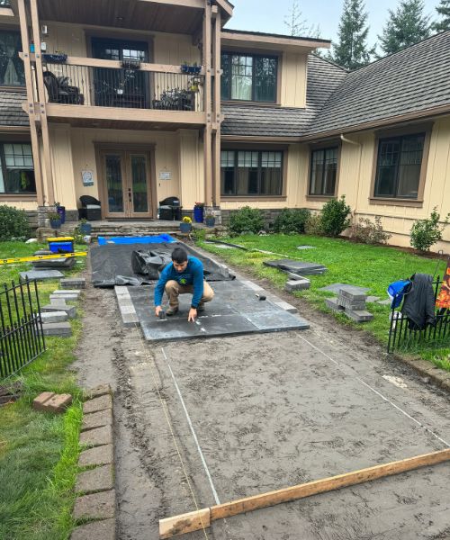 A man working on a concrete slab in front of a house